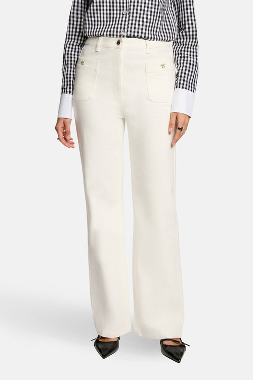 Jeans coloré blanc de Morgan de Toi, avec poches décoratives et porté avec une chemise à carreaux.
