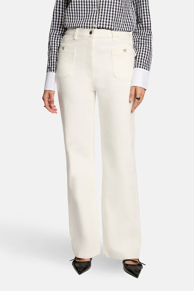 Jeans coloré blanc de Morgan de Toi, avec poches décoratives et porté avec une chemise à carreaux.
