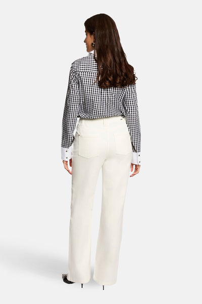 Jean coloré blanc de Morgan de Toi, coupe droite, poches arrières apparentes, porté avec une chemise à carreaux.
