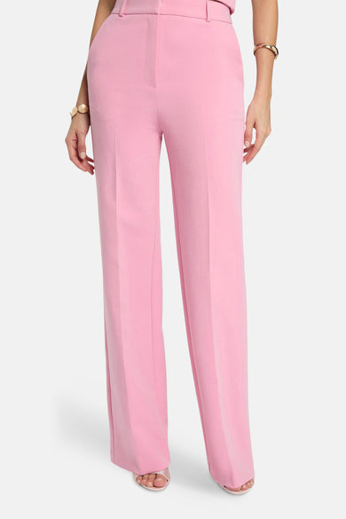Pantalon de costume rose van Morgan de Toi, coupe droite, avec plis et bracelet doré.
