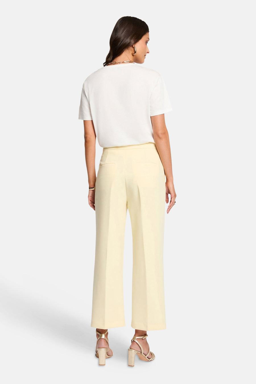 Pantalon jaune de Morgan de Toi, coupe large, porté avec un t-shirt blanc et des talons dorés.