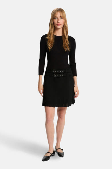 Robe noire 3/4 de Morgan de Toi avec ceinture à boucle et jupe plissée, portée avec des chaussures noires.
