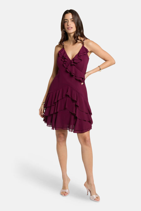 Bordeaux jurk van Morgan de Toi, met decoratieve ruches, gedragen met glanzende pumps en een gouden armband.