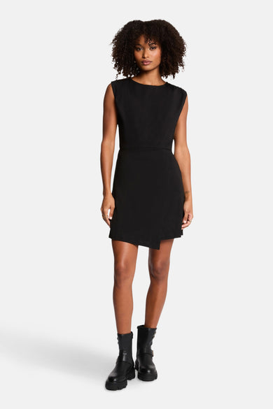 Robe noire de Morgan de Toi avec une coupe portefeuille asymétrique et des bottes noires.

