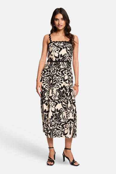 Robe noire et beige de Morgan de Toi, mi-longue à motif feuilles et col carré festonné, portée par un mannequin avec des sandales noires.