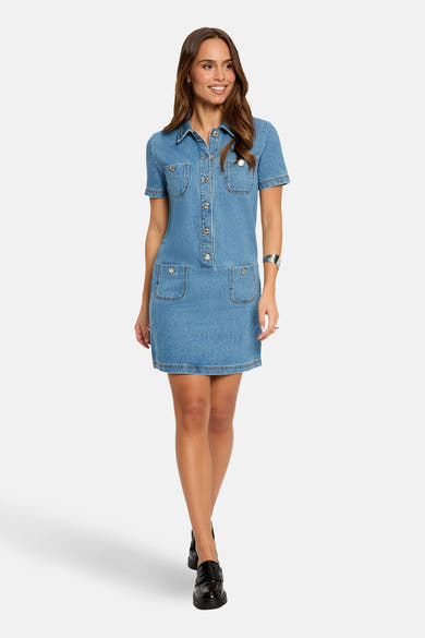 Robe en denim bleu moyen de Morgan de Toi avec des poches plaquées et des boutons décoratifs, portée avec des chaussures noires.
