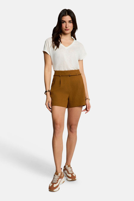 Korte, getextureerde bruine broek van Morgan de Toi, hoge taille met ceintuur, gedragen met een wit T-shirt en tweekleurige sneakers.
