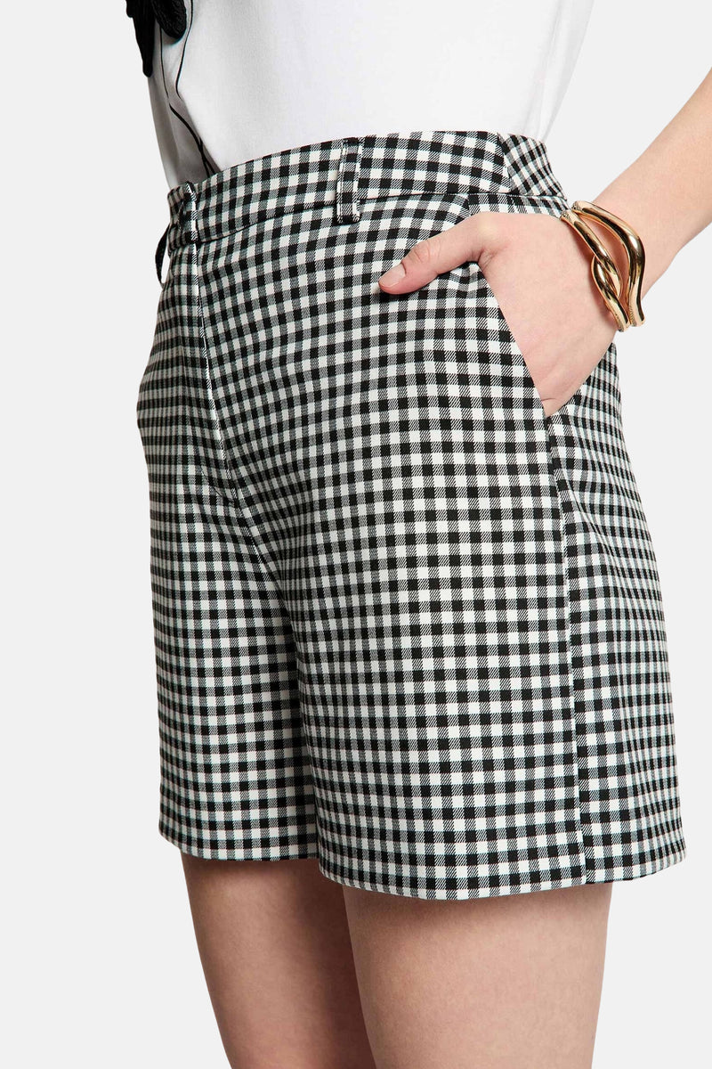 Short noir à carreaux vichy de Morgan de Toi, avec une main dans la poche et un bracelet doré.
