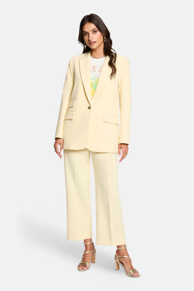 Blazer jaune de Morgan de Toi, porté avec un t-shirt imprimé et un pantalon assorti.