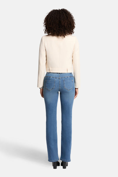 Veste courte écru de Morgan de Toi, avec une ceinture, portée avec un jean bleu.