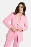 Blazer rose de Morgan de Toi, porté par une femme avec des boucles d'oreilles dorées et un bracelet orné.
