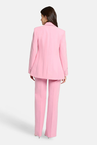Blazer rose de Morgan de Toi, avec une coupe ajustée et des détails de boutons aux poignets, porté avec un pantalon assorti.
