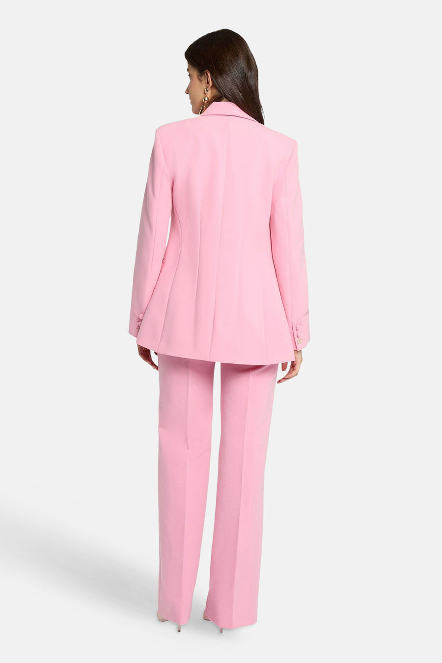 Blazer rose de Morgan de Toi, avec une coupe ajustée et des détails de boutons aux poignets, porté avec un pantalon assorti.
