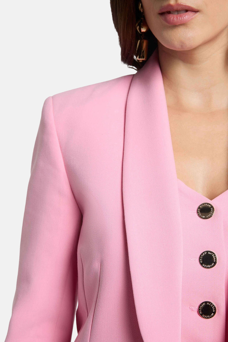 Blazer rose de Morgan de Toi avec boutons décoratifs et revers structuré, porté avec boucles d'oreilles pendantes.
