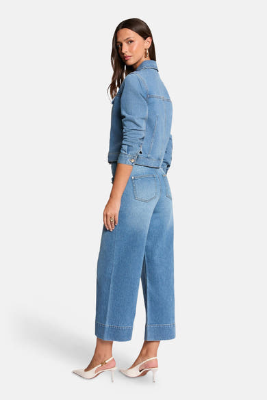 Veste courte en denim bleu moyen de Morgan de Toi, portée avec un jean large et des escarpins blancs.
