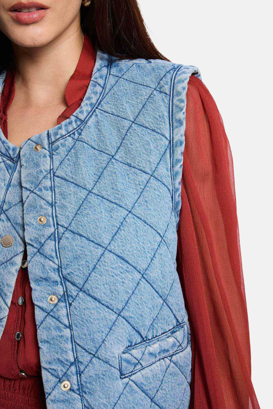 Veste sans manches en denim bleu clair de Morgan de Toi, matelassée à carreaux, portée sur un chemisier bordeaux.
