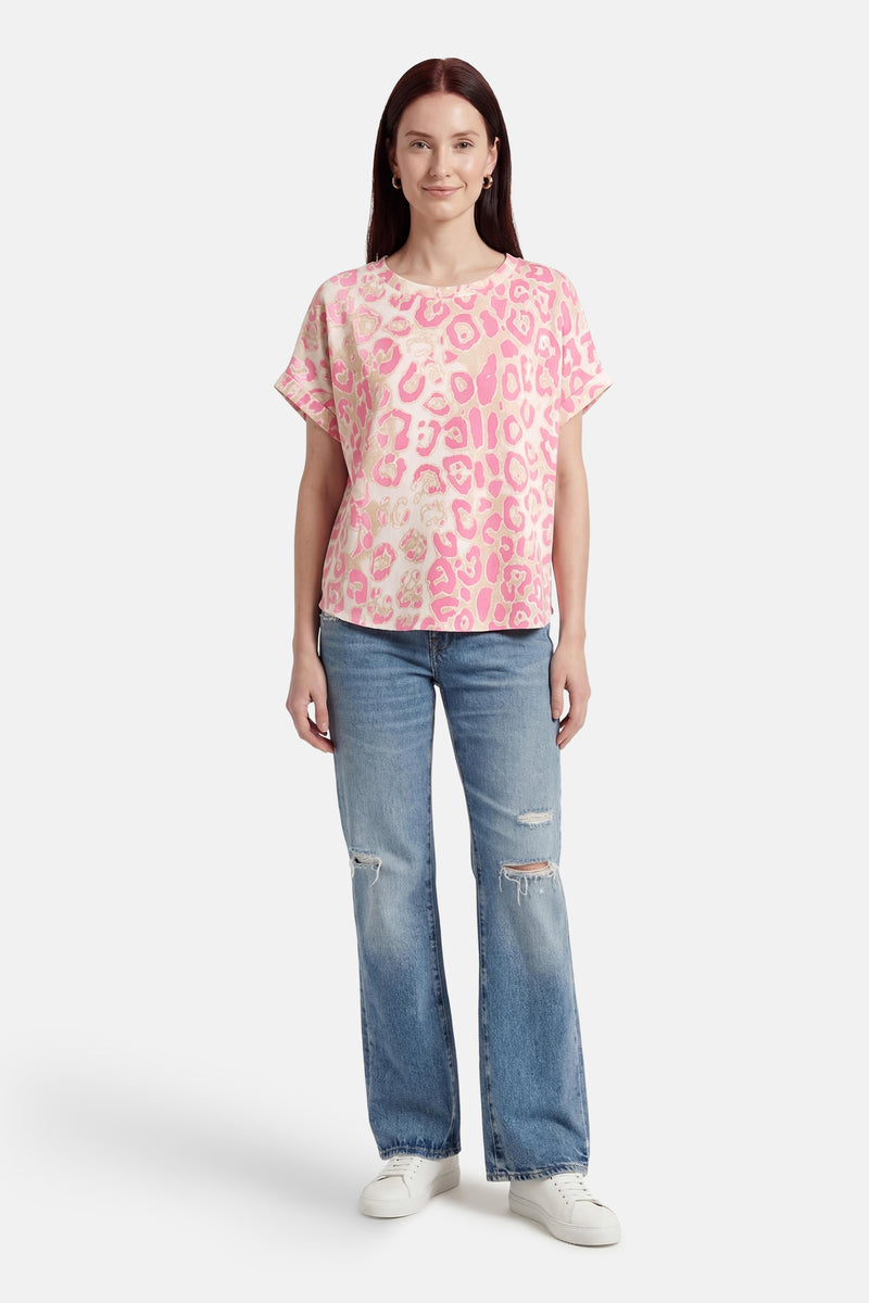 T-shirt rose à manches courtes de Terra di Siena avec un motif léopard, porté avec un jean bleu délavé et des baskets blanches.
