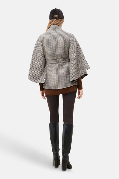 Poncho à carreaux multicolore CAROLL, vu de dos, porté avec un pull marron et des bottes noires