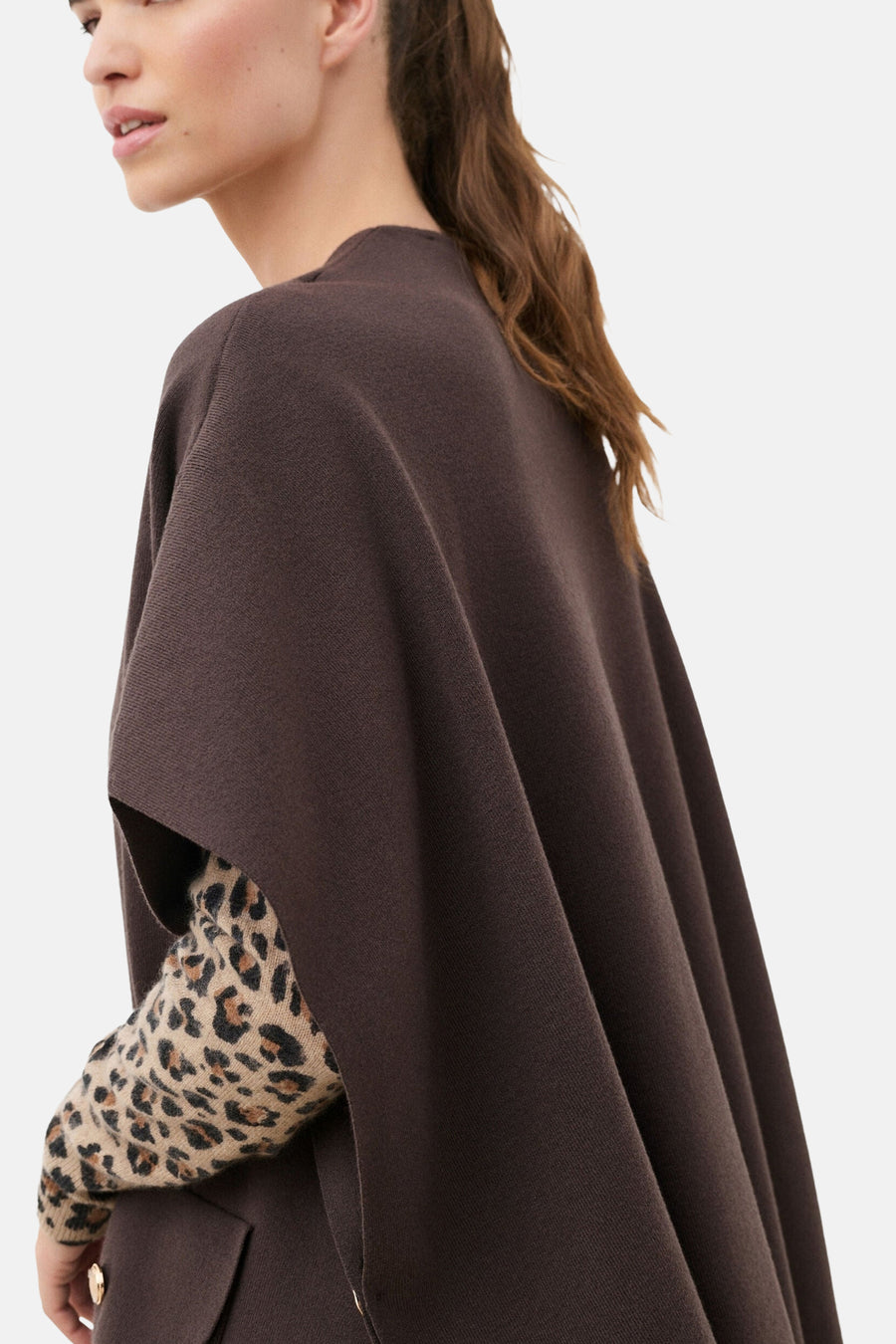 Brown knit gilet by CAROLL, side view showing draped silhouette with gold buttons and leopard-print sleeve underneath.