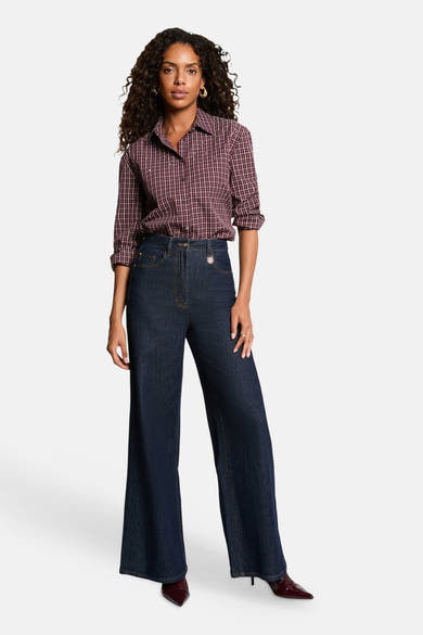Red long-sleeve checkered blouse with button-down front, worn with dark denim flared jeans and burgundy pointed-toe heels, full-body lifestyle view