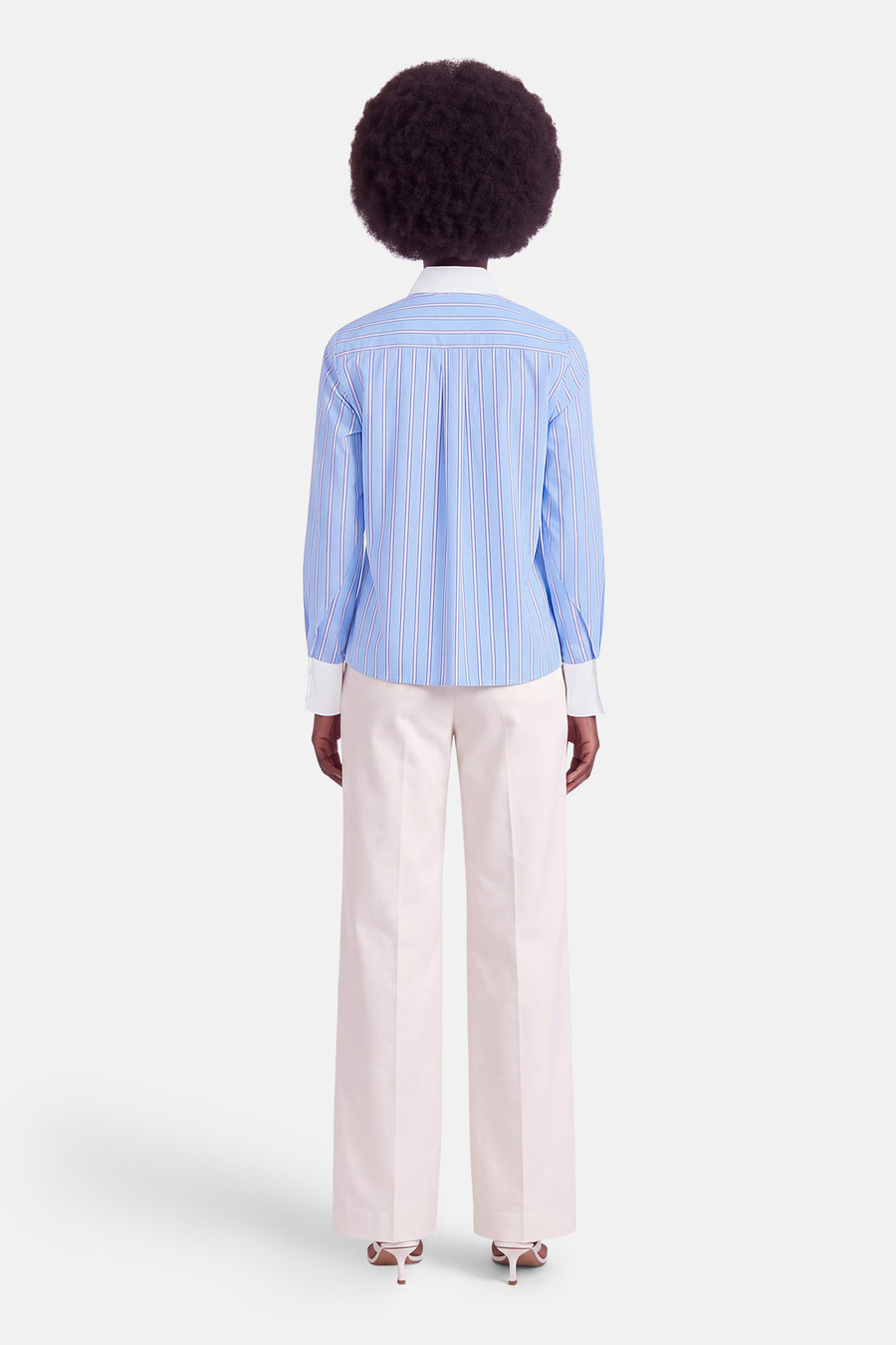 Chemise bleue à rayures fines, vue dos, par Morgan de Toi, avec col blanc et manches longues, portée avec pantalon clair et chaussures à talons.