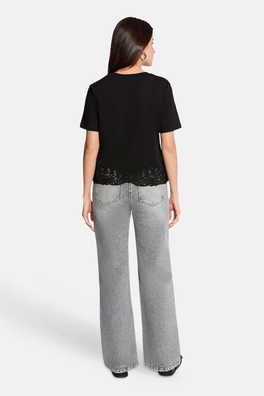 Black short-sleeve t-shirt with lace trim hem, back view, worn with gray wide-leg jeans