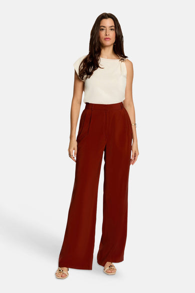 Écru sleeveless top with shoulder embellishment, front view, paired with wide-leg burgundy trousers and gold sandals