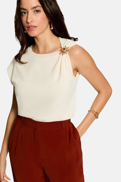 Écru sleeveless top with gold sun brooch detail, side view, paired with burgundy trousers
