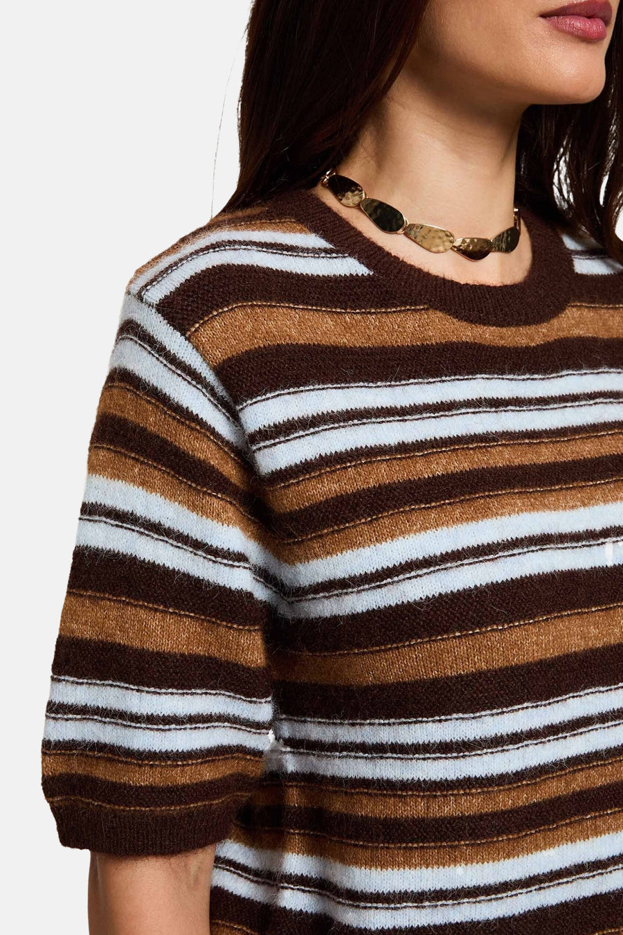 Multicolored striped round-neck sweater with brown, white, and tan horizontal bands, textured knit, short sleeves, side view on model wearing gold leaf necklace