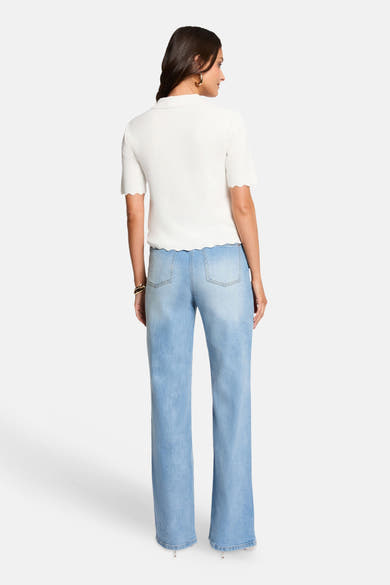 White short-sleeve ribbed knit O-neck pullover, back view, paired with light blue wide-leg jeans and gold hoop earrings