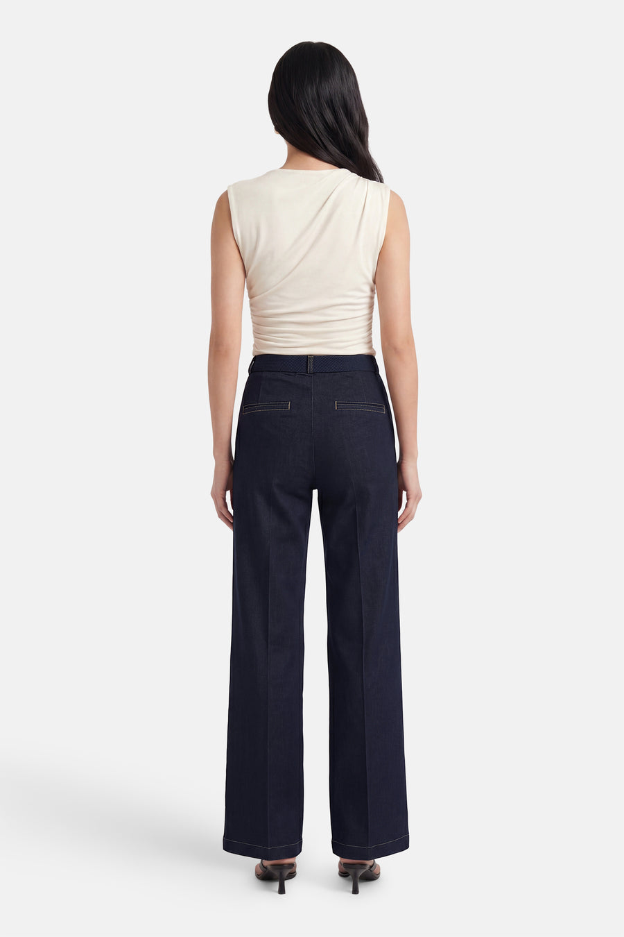 Dark blue wide-leg denim jeans by MIRA, back view, featuring clean stitching and structured fit, worn with cream top and heels.