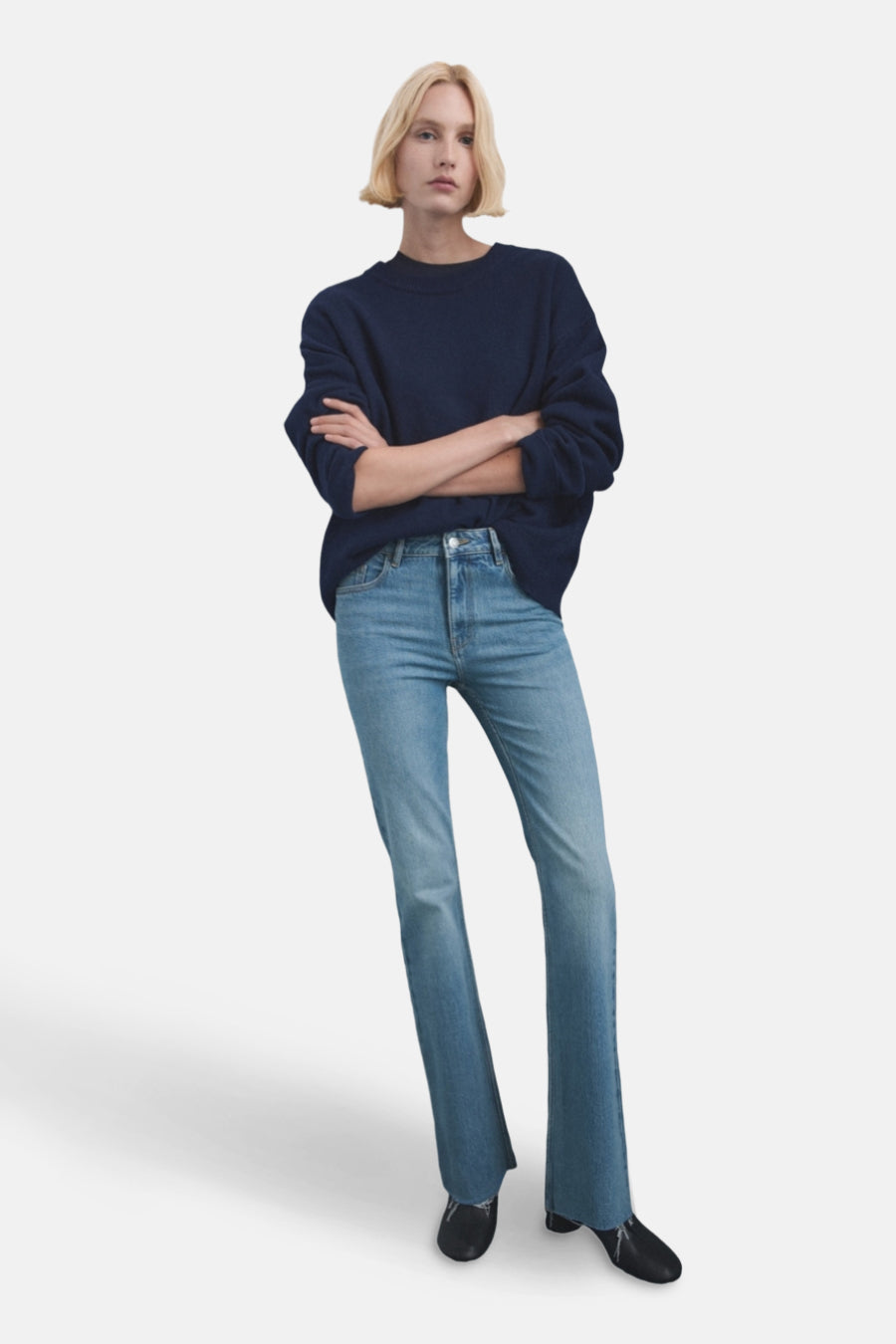 Jean évasé bleu clair de MANGO, porté avec un pull bleu marine et des chaussures noires.