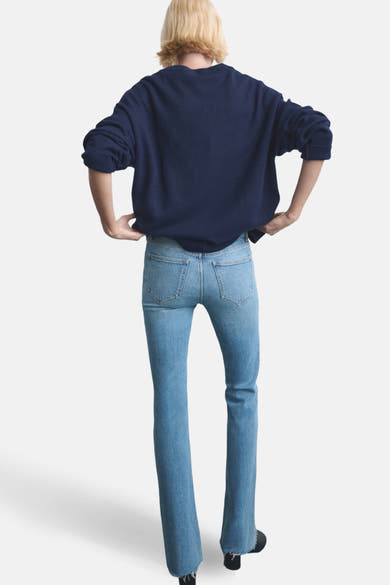 Jean évasé bleu clair de MANGO, vue arrière avec un pull bleu marine et des chaussures noires.