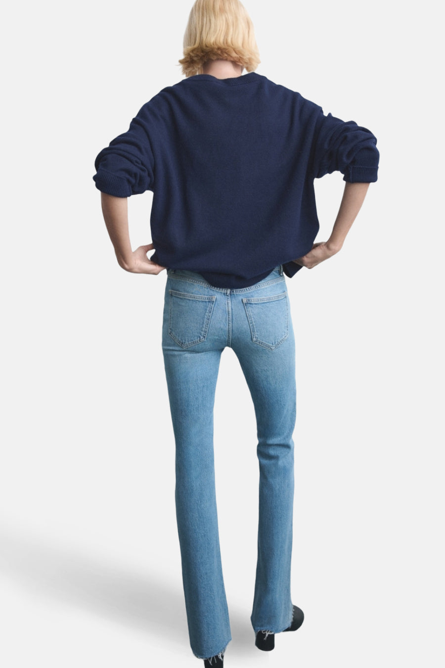 Jean évasé bleu clair de MANGO, vue arrière avec un pull bleu marine et des chaussures noires.