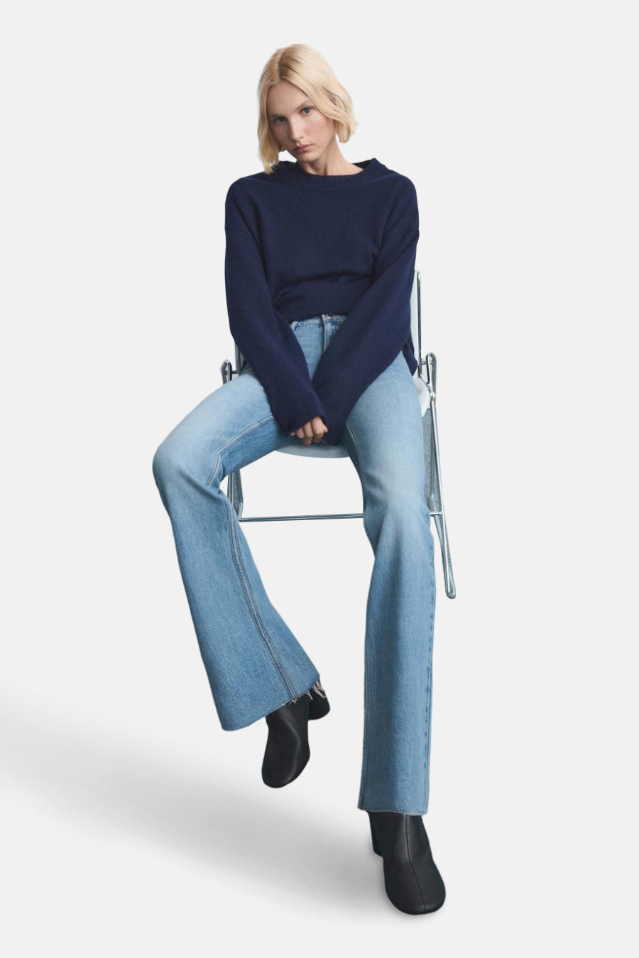 Jean évasé bleu clair de MANGO, porté avec un pull marine et des bottines noires.
