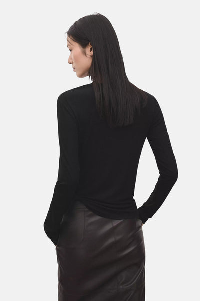 Black long-sleeve t-shirt from back view, fitted with smooth texture, worn with black leather skirt