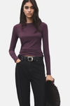 T-shirt à manches longues bordeaux de MANGO, porté avec un jean noir et une ceinture à boucle argentée.
