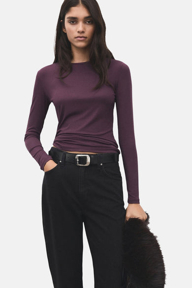 T-shirt à manches longues bordeaux de MANGO, porté avec un jean noir et une ceinture à boucle argentée.

