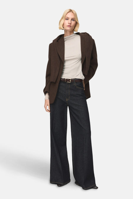 T-shirt beige à manches longues de MANGO, porté avec un blazer marron et un pantalon denim large.