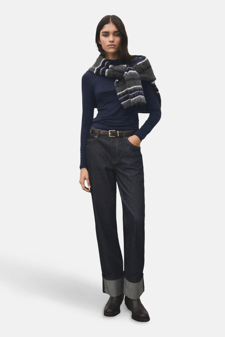 T-shirt à manches longues bleu de MANGO, porté avec un jean et un foulard rayé sur les épaules.