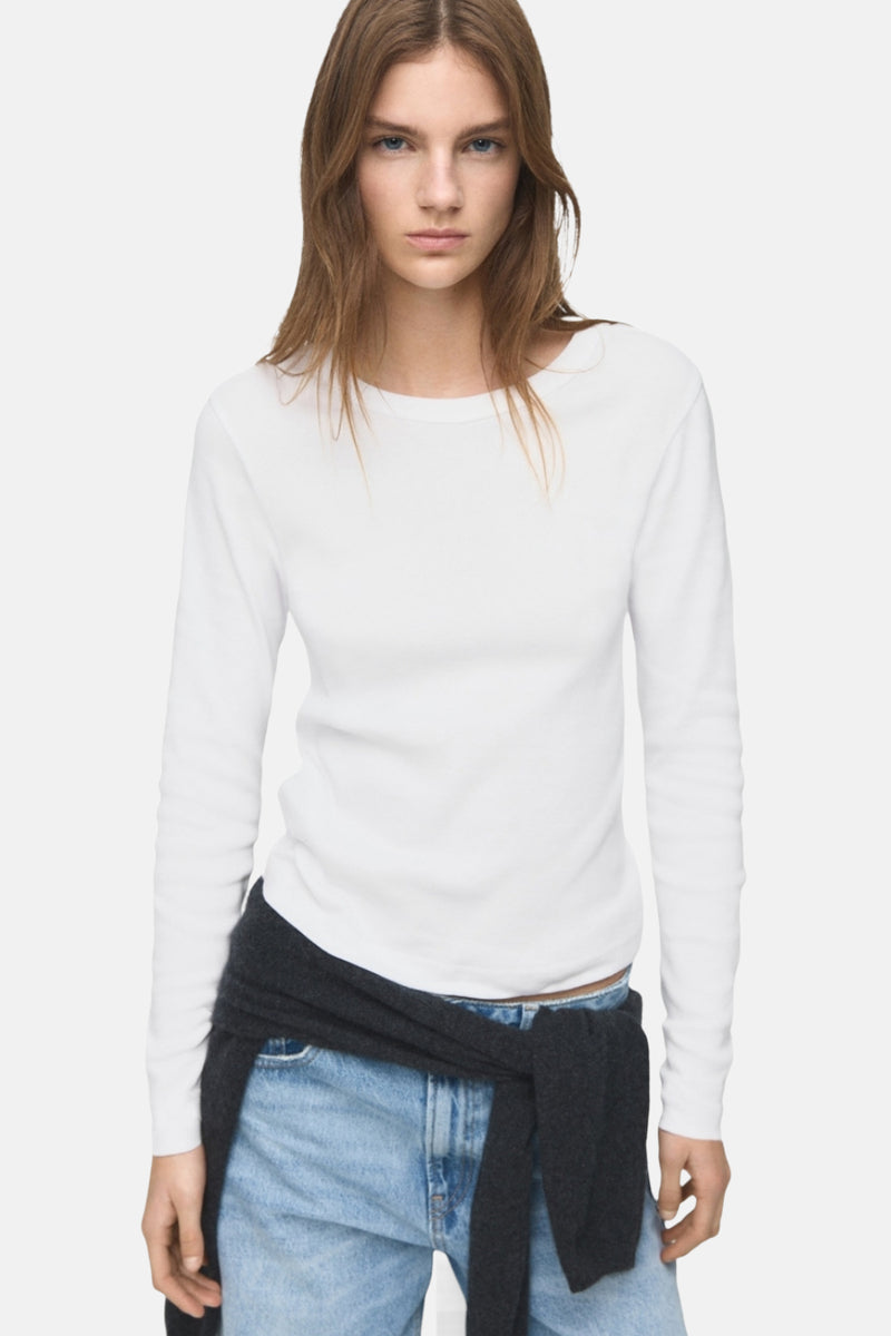 T-shirt à manches longues blanc de MANGO, porté avec un pull en maille gris noué autour de la taille et un jean bleu clair.