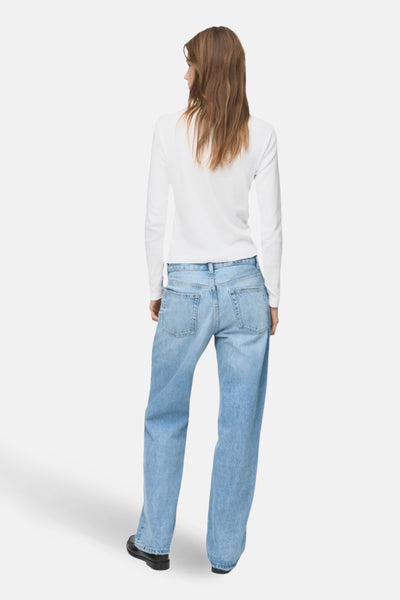 T-shirt à manches longues blanc de MANGO, porté avec un jean décontracté bleu clair et des chaussures noires.