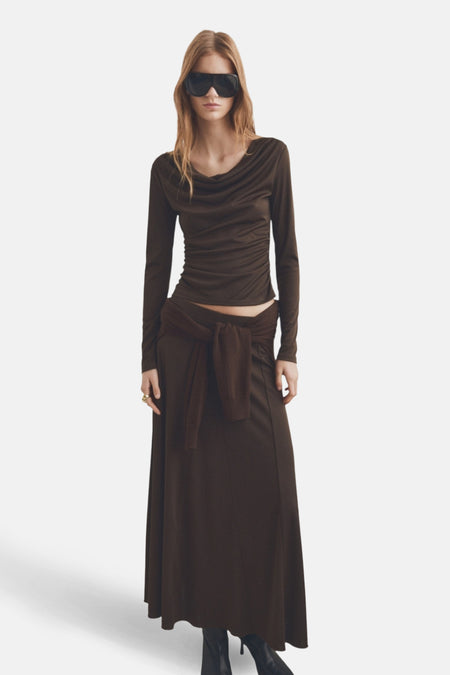 T-shirt à manches longues brun de MANGO, avec un drapé au niveau du cou, porté avec une jupe longue.
