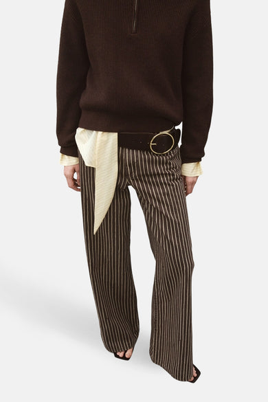 Jeans coloré brun de MANGO, avec motif rayé vertical, ceinture marron et boucle dorée.
