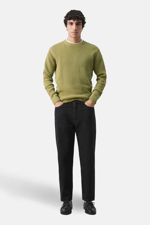 Pull à col rond vert de MANGO, porté avec un jean noir et des chaussures bateau.