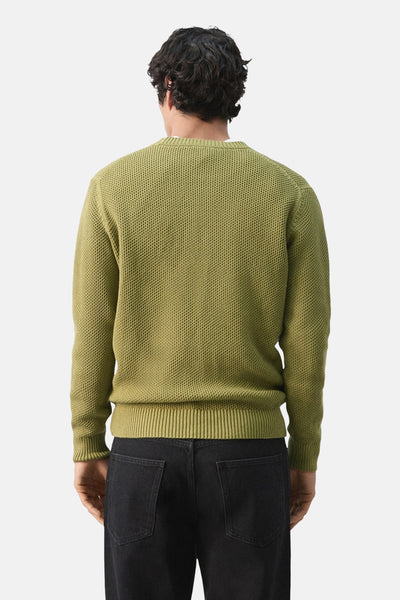 Pull à col rond vert de MANGO, en maille texturée, porté avec un jean noir vu de dos.
