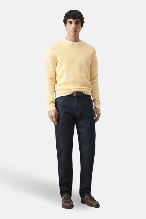 Pull à col rond jaune par MANGO, avec une texture gaufrée et porté avec un jean et des chaussures bateau.
