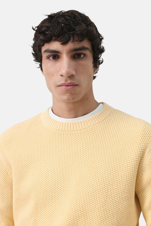 Pull à col rond jaune de MANGO, en maille texturée avec un col ras du cou blanc en dessous.