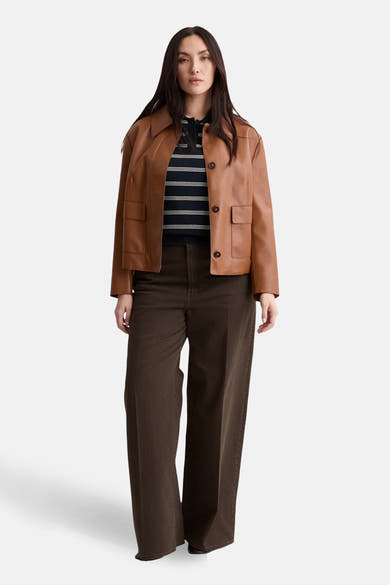 Polo à manches courtes bleu de MANGO, porté avec une veste marron clair et un pantalon marron foncé.