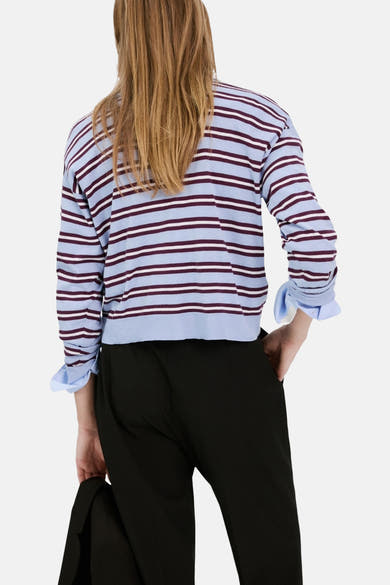 Pull col rond multicolore de MANGO, à rayures bleues et bordeaux, porté avec un pantalon noir.